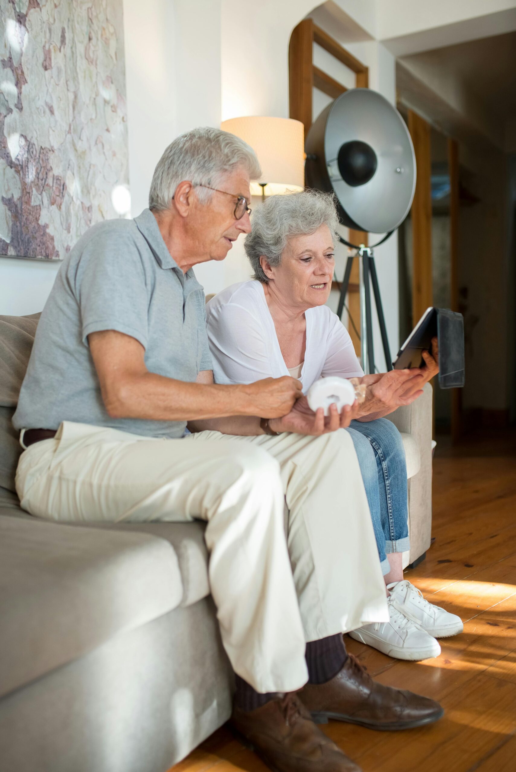 pexels-photo-8949846-8949846 Elderly couple enjoying leisure time indoors using a tablet on a comfortable sofa.